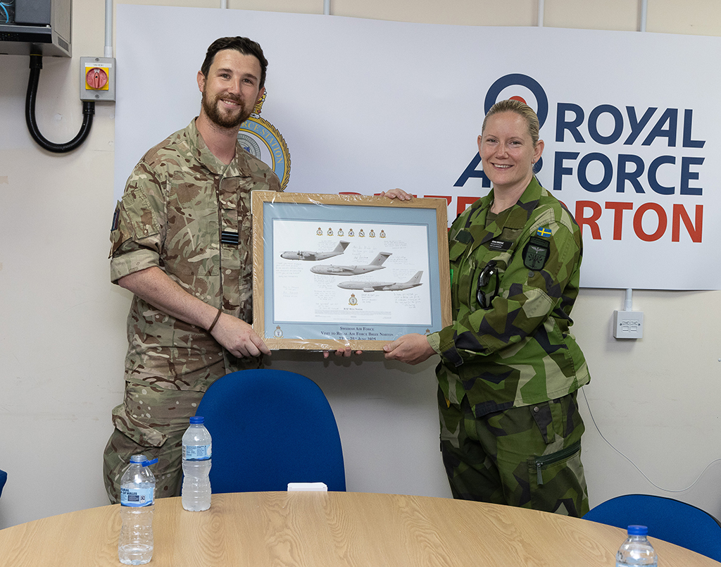 Flight Lieutenant Aidan passes a framed print of the Atlas (A400M), Globemaster (C-17) and a Voyager to Captain Anna Obrovac of the Swedish Airforce as a momento of their visit.